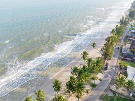 The ariel view of the clear sky with palm tr ees, fine sand and foam waves splashed to serene beach in Chumphon, Thailand. photo