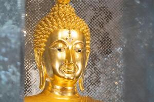 close up of golden Buddha statue is a stunning sig ht to behold. The intricate details and craftsmanship of the sculpture are clearly visible, showcasing the skill and talent of artist who created it. photo