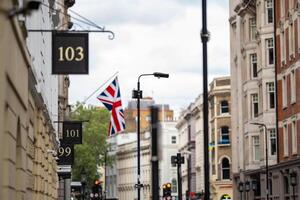 London street captures the essence of British heritage with classic architecture, numbered storefronts, and a Union Jack flag adding a patriotic touch. photo