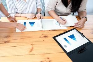 Employees Meeting in conference room. There ar e triangular diagrams, graphs, and related data set aside on a long brown wooden table. photo