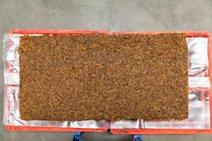 The close up image of the jagged brown natural ra w rubber bales surface, lumpy solid block standard Thai rubber, in a factory. photo