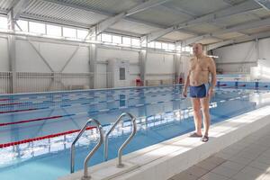 A 70-year-old pensioner is resting, swimming, recovering in the pool with clear and blue water hotel. photo