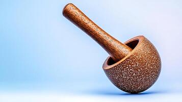 Wooden mortar and pestle resting on a soft blue background, highlighting its craftsmanship and texture photo