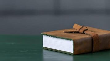 A close-up of a brown leather-bound notebook resting on a green surface in a minimalist setting photo