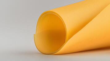 Close-up of a rolled sheet of vibrant yellow material on a neutral background, showcasing texture photo
