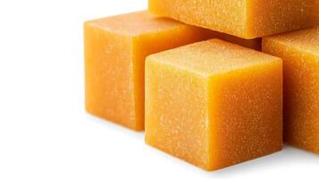 Close-up of stacked orange soap cubes on a white background, showcasing texture and color photo