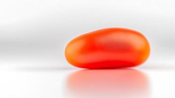 A smooth, shiny red object resembling a bean, placed on a reflective surface with soft lighting photo