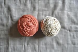 light orange and white colour two yarn ball and background is a gray linen fabric photo