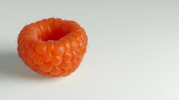 Close-up of a vibrant, orange raspberry showcasing its textured surface against a plain background photo
