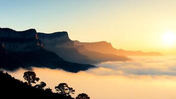 Sunrise over misty mountains with silhouettes of trees and peaks against a colorful sky photo