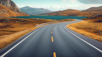 Serene winding road through autumn landscape near a tranquil lake and distant mountains photo