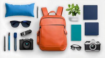Stylish orange backpack surrounded by sunglasses, notebooks, and plants on a clean surface photo