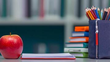 A vibrant red apple next to a stack of colorful notebooks and pencils in a study area photo