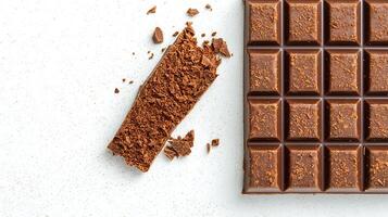 Close-up of a broken chocolate bar with scattered cocoa crumbs on a light background photo
