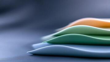 Close-up of colorful, wavy silicone sheets stacked on a smooth surface with soft lighting photo
