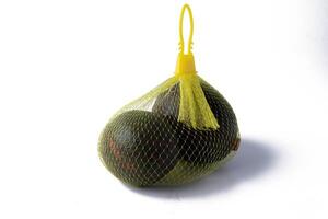 mesh bag containing fresh avocados is displayed against white background, highlighting vibrant green color and texture of fruit photo