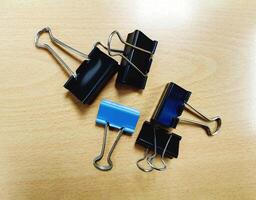 Many black and blue paper clips on wooden table with copy space. Office object on wood background concept photo