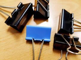 Many black and blue paper clips on wooden table. Office object on wood background concept photo