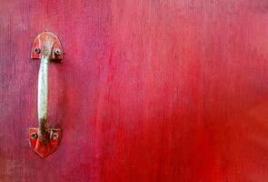 Close up metal handle of door or window on red wooden background painted with copy space. Art and Abstract wallpaper concept. photo