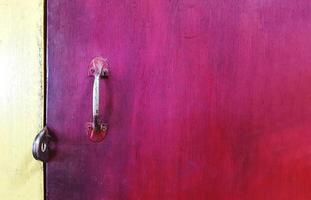 Close up metal handle of door or window on red wooden background painted with copy space. Art and Abstract wallpaper. photo