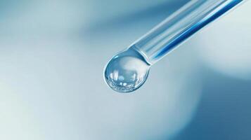 Close-up of dropper with liquid droplet against blurred blue background photo