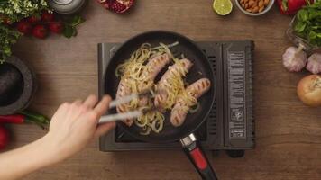 Crop anonymous person adding onion into pan with sausages video