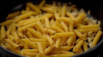Anonymous cook putting raw macaroni in pan with fried onion video