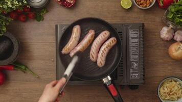 Overhead view of turning homemade sausages frying in pan using foodclamp video