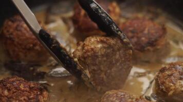 Closeup of anonymous person turning cutlets in sauce video