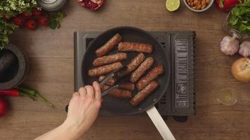 Overhead view of person turning homemade sausages frying in pan video