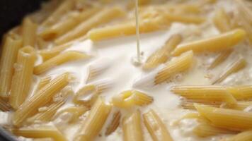Adding cream into frying pan of macaroni video