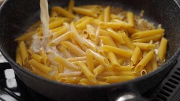 cook adding cream into frying pan with macaroni video