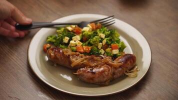 Shoot of a person putting fork on plate with salad and sausages video