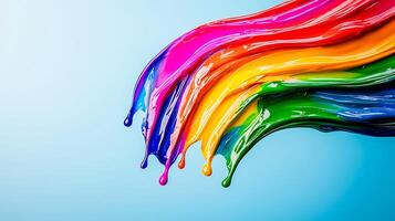 Vibrant streams of paint in rainbow colors flowing gracefully against a soft blue background photo