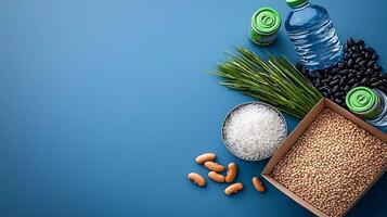 Assorted grains, beans, and water bottles arranged on a blue background for healthy lifestyle promotion photo