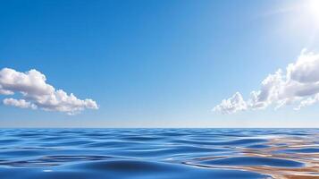 Tranquil ocean waves under a clear blue sky with soft clouds and bright sunlight in the background photo