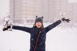 Portrait of 12 year old girl in a warm jacket and a cat-ear hat under heavy snow photo