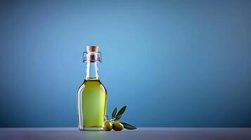 A glass bottle of olive oil with fresh olives and leaves on a minimalist blue background photo