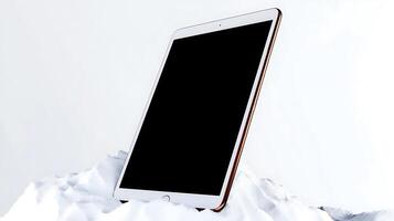 A sleek tablet resting on a snow-covered mountain peak, showcasing modern technology in nature photo
