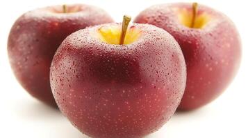 Three fresh red apples with droplets of water on them, showcasing their vibrant color and texture photo