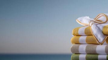 Stacked towels in vibrant colors on a serene beach with a calm ocean background photo