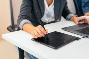 Close-up of an unrecognizable woman using a graphics tablet for working photo