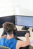 From above, software engineer sitting at desk and typing on computer keyboard while creating code during work at home. photo