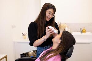 Beautician making eyelash lamination and dyeing procedures while explaining the process photo