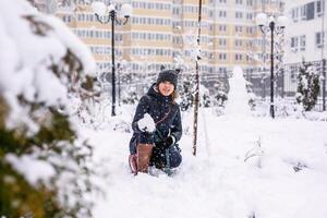 A funny teenage girl sits with her dog in the snow in winter, throwing snowballs at her. Russian spaniel runs with flapping ears in the snow and plays photo