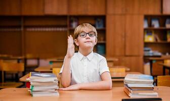 Student boy reading book and looking very surprised in the school classroom photo