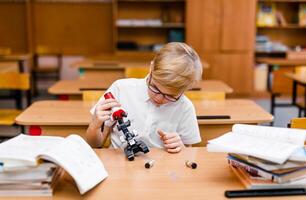 Boy with visual impairment in glasses carefully studying textbooks at desk photo