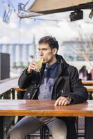 Man drinking a lemonade while sitting in a bar at the harbor photo