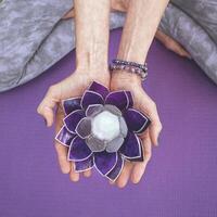 Top angle view of hands holding a purple glass lotus. Yoga and meditation concept. photo