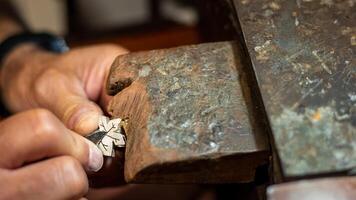 Goldsmith working and creating in his crafting gold jewelry workshop with a burin. Jeweler repairing a silver jewel. photo